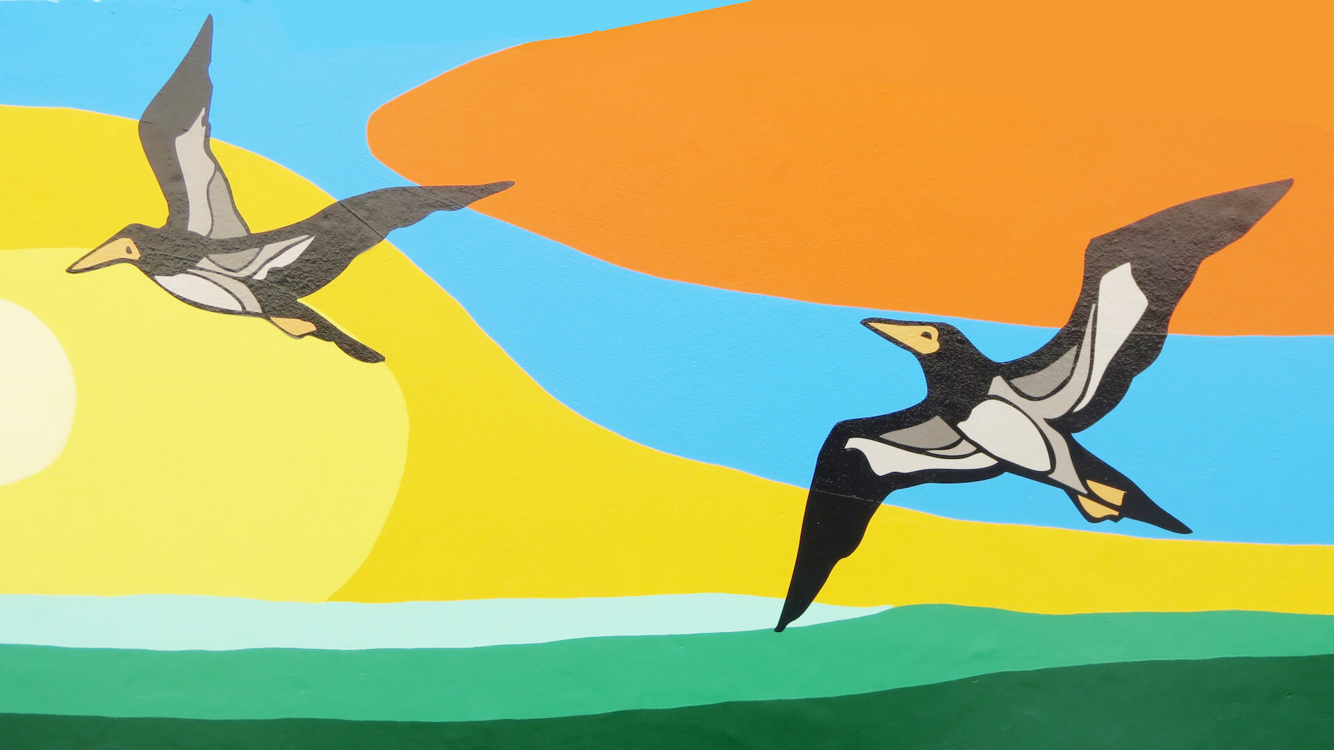 Mural pintado com dois atobás voando sobre o mar